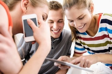 Three young adult friends looking at digital tablet
