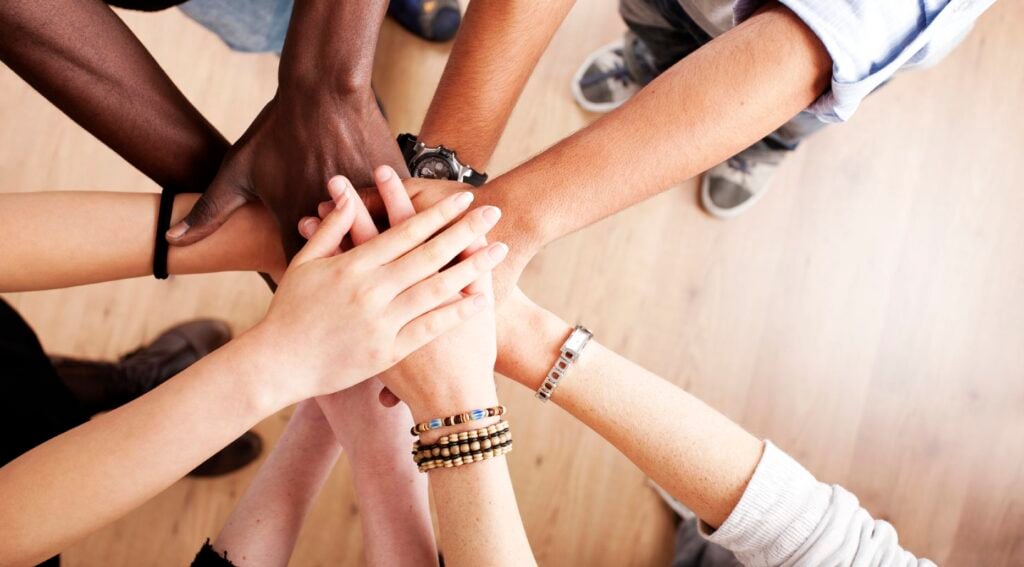 Diverse team stacking hands in unity indoors