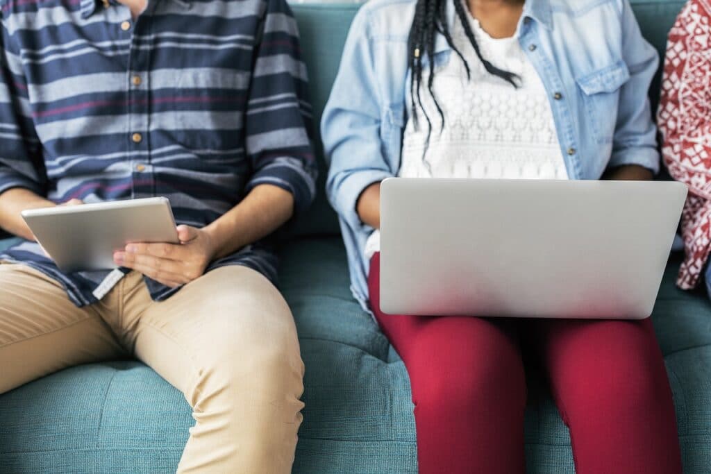 People sitting on couch using laptop and tablet