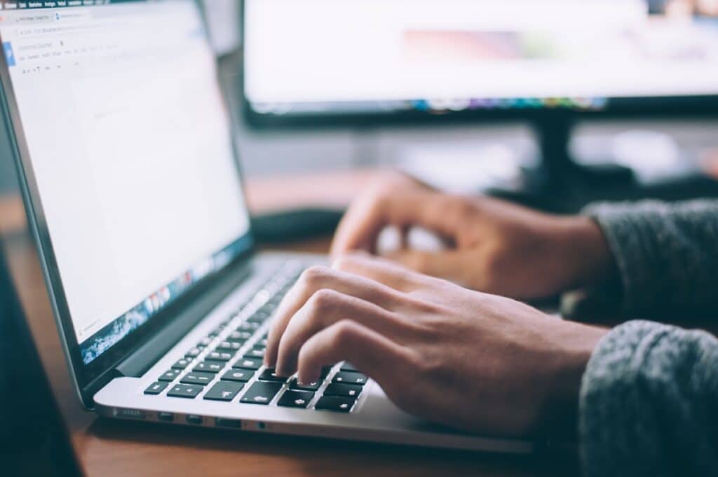 Hands typing on laptop keyboard at desk