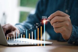 Person using a laptop with a rising bar chart showing growth to 2024