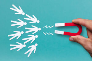 Hand holding a magnet attracting paper cut-out people figures
