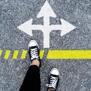 Person standing at a crossroads with arrows pointing in different directions