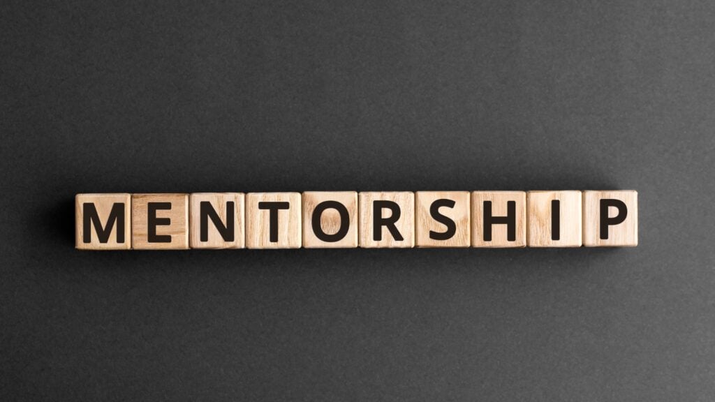 Wooden blocks spelling out "MENTORSHIP" against a dark gray background.