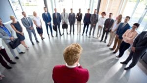 A person in a red suit standing before a large group of diverse business professionals