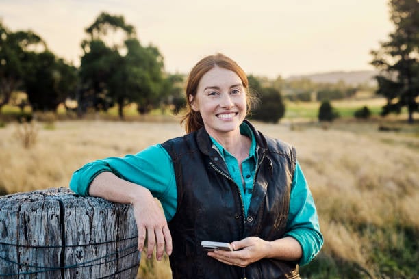 Young female farmer staying in touch via mobile technology from her farm in rural Tasmania, Australia.