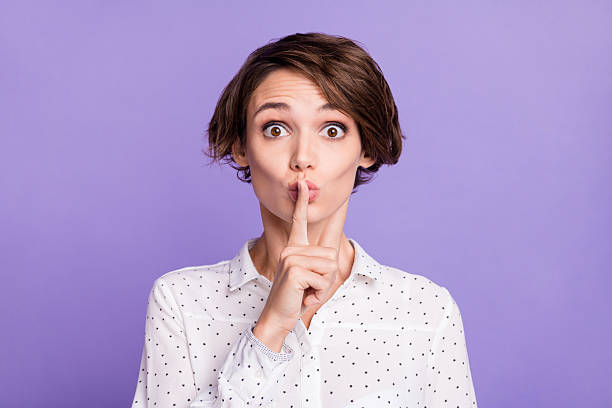 Photo of charming young lady finger covering mouth lips do not tell isolated on violet color background