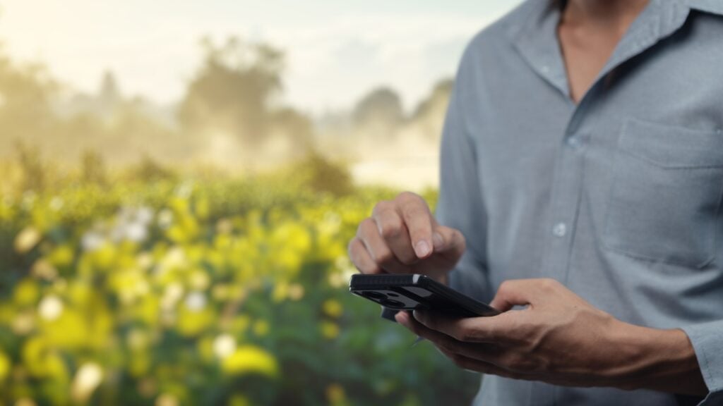A hand of a manager wearing a light blue button-down shirt as they type on a smartphone.